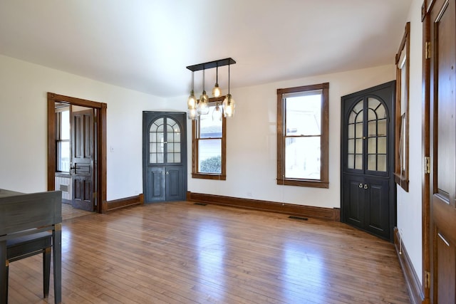 entrance foyer featuring a chandelier, baseboards, visible vents, and hardwood / wood-style floors