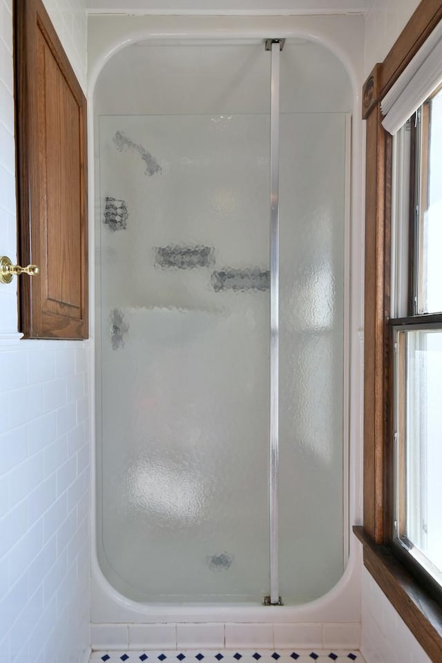 bathroom with a shower stall and tile walls