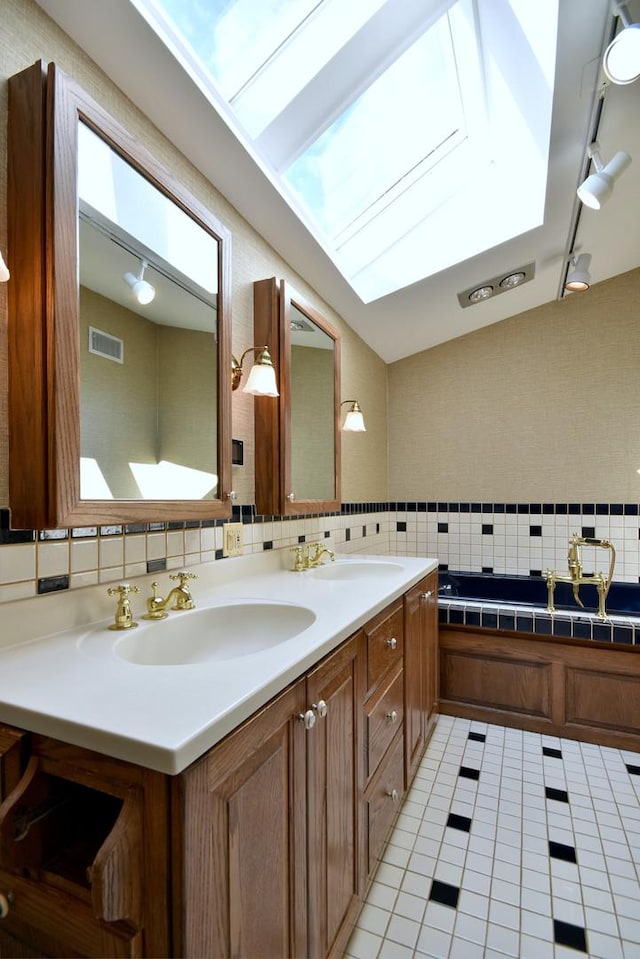 bathroom with double vanity, a skylight, visible vents, tile patterned floors, and a sink