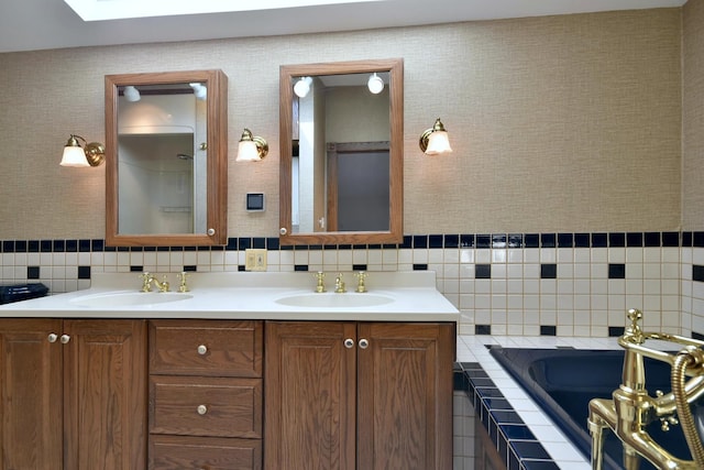 bathroom featuring a relaxing tiled tub, tasteful backsplash, a sink, and double vanity