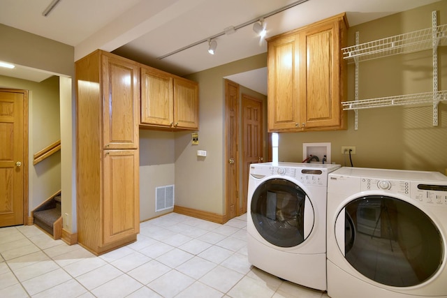 laundry area with light tile patterned flooring, separate washer and dryer, visible vents, baseboards, and cabinet space