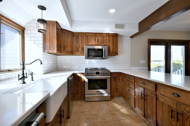 kitchen featuring light countertops, appliances with stainless steel finishes, brown cabinetry, and backsplash