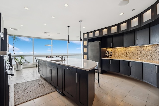 kitchen featuring a kitchen bar, sink, a water view, hanging light fixtures, and an island with sink