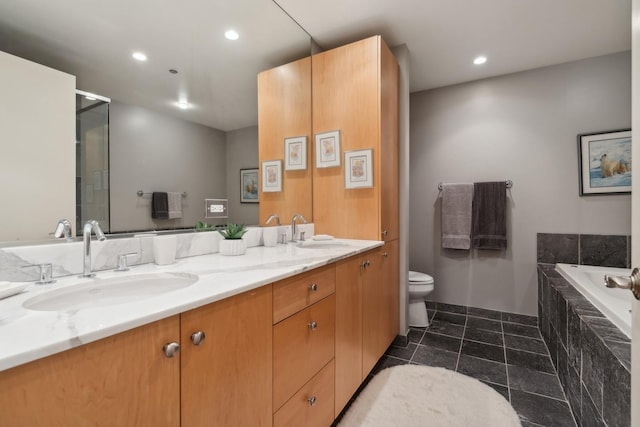 bathroom with a relaxing tiled tub, vanity, and toilet