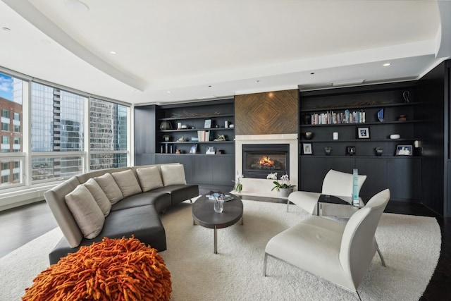 living room with wood-type flooring, a raised ceiling, and built in features