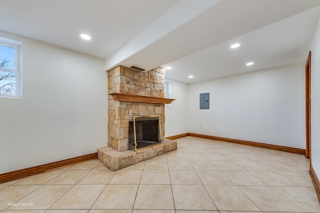 unfurnished living room with light tile patterned flooring, a stone fireplace, and electric panel