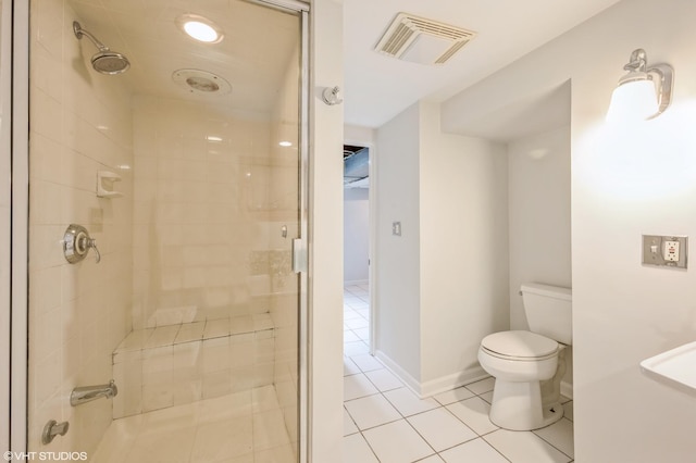 bathroom with tile patterned flooring, a tile shower, and toilet