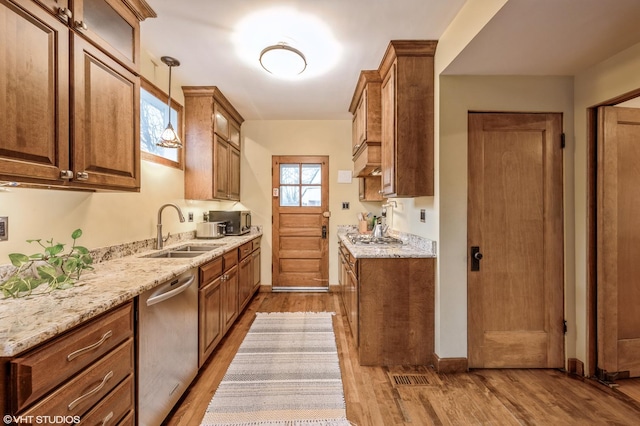 kitchen with light hardwood / wood-style flooring, dishwasher, light stone countertops, pendant lighting, and sink