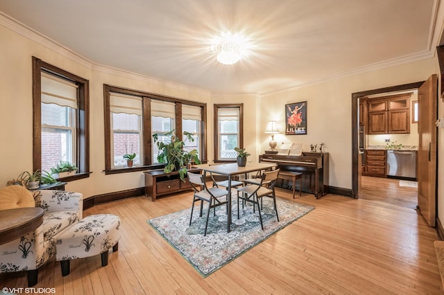 dining room featuring light wood-type flooring, crown molding, and a healthy amount of sunlight