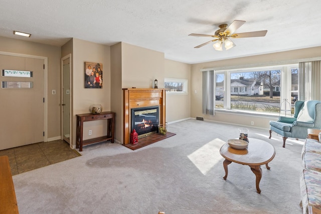 living room featuring ceiling fan, light carpet, and a textured ceiling