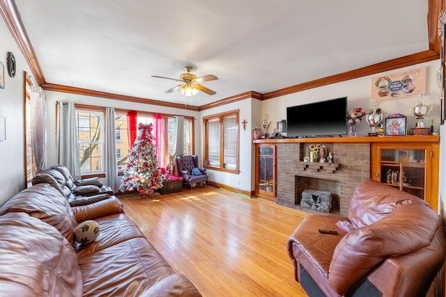 living room with ceiling fan, ornamental molding, a fireplace, and light hardwood / wood-style floors