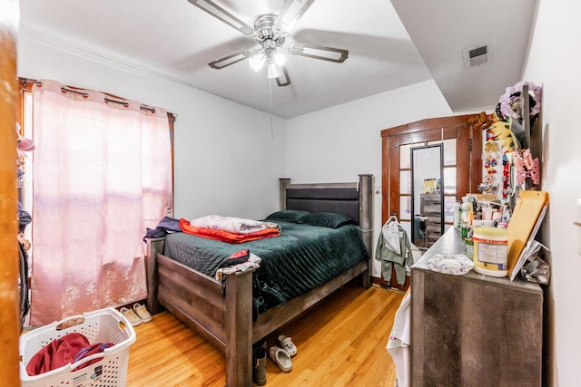 bedroom with crown molding, light hardwood / wood-style floors, and ceiling fan