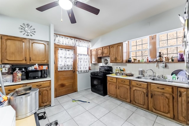 kitchen featuring sink, decorative backsplash, light tile patterned floors, ceiling fan, and black appliances