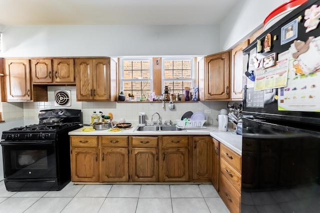 kitchen featuring tasteful backsplash, sink, light tile patterned floors, and black appliances