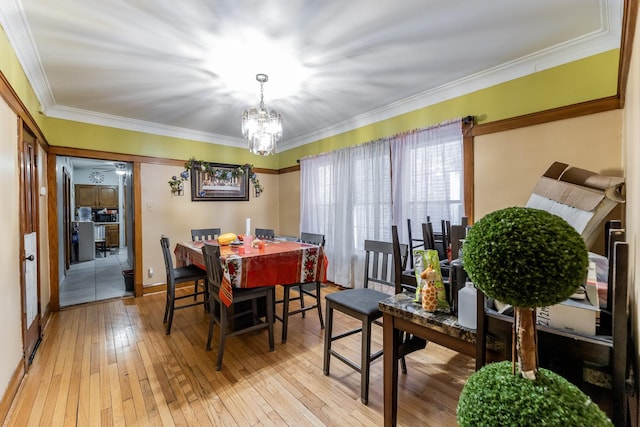 dining area featuring ornamental molding, an inviting chandelier, and light wood-type flooring