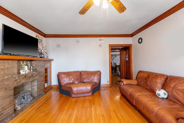 living room with ceiling fan, crown molding, a fireplace, and wood-type flooring