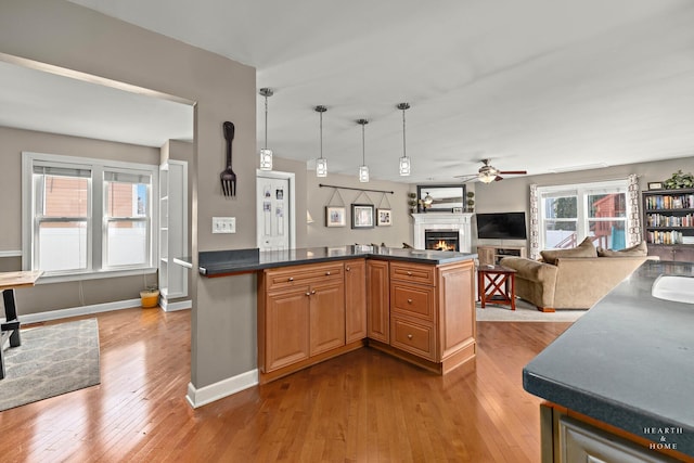 kitchen with dark countertops, hardwood / wood-style flooring, a lit fireplace, and open floor plan