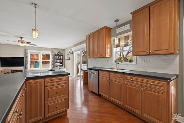 kitchen featuring dark countertops, a sink, brown cabinetry, and dishwasher