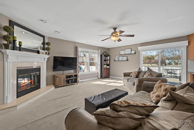 living room featuring light carpet, ceiling fan, a fireplace, and baseboards