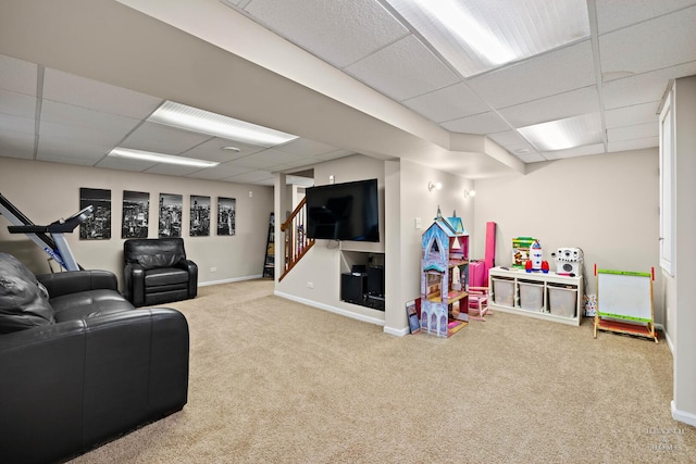 living room featuring baseboards, a drop ceiling, carpet flooring, and stairs