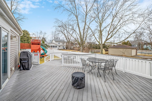 deck featuring a fenced backyard, a residential view, a playground, and outdoor dining space