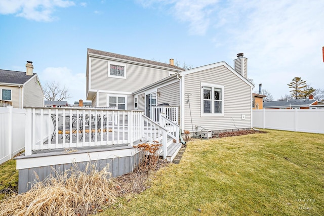 rear view of property with a deck, a lawn, and fence