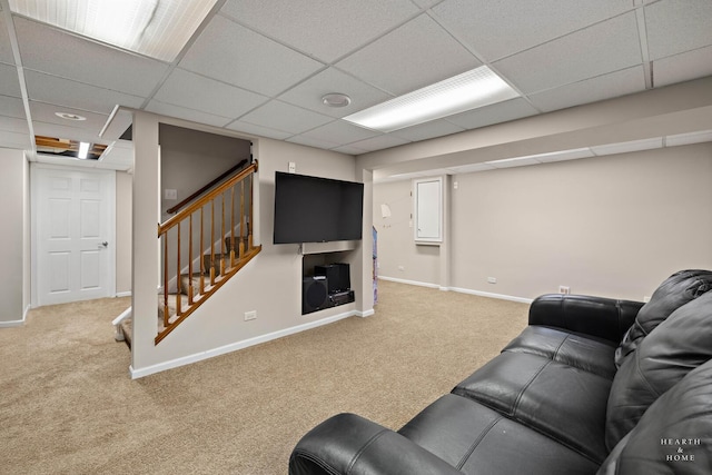 carpeted living area featuring stairs, a paneled ceiling, and baseboards