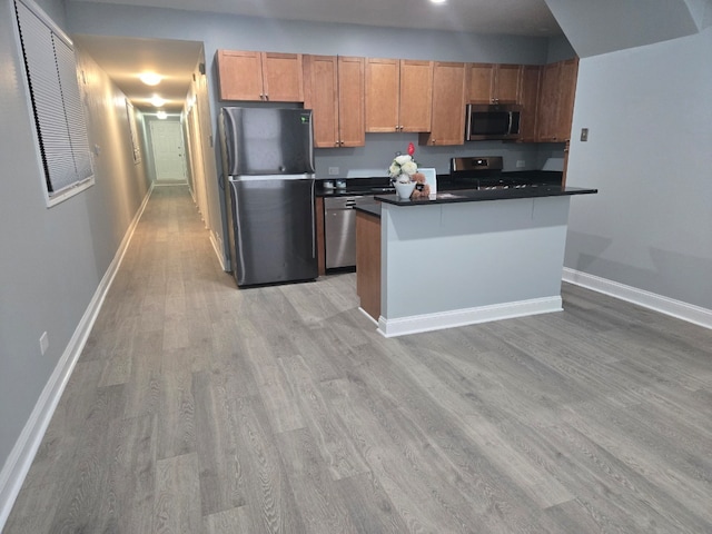 kitchen with appliances with stainless steel finishes, a center island, and light hardwood / wood-style flooring