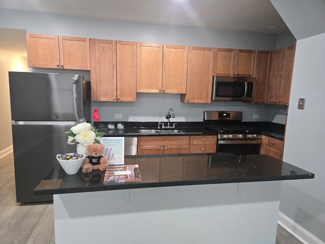 kitchen featuring appliances with stainless steel finishes, sink, a kitchen bar, and light hardwood / wood-style flooring