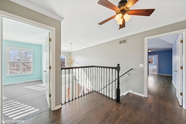 hallway with dark wood-type flooring, ornamental molding, and a chandelier