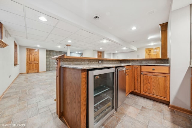 kitchen featuring beverage cooler, kitchen peninsula, and refrigerator