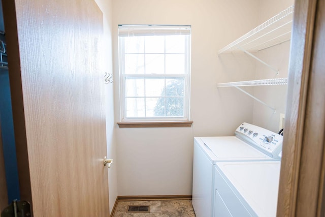 clothes washing area featuring laundry area, washing machine and dryer, visible vents, and baseboards