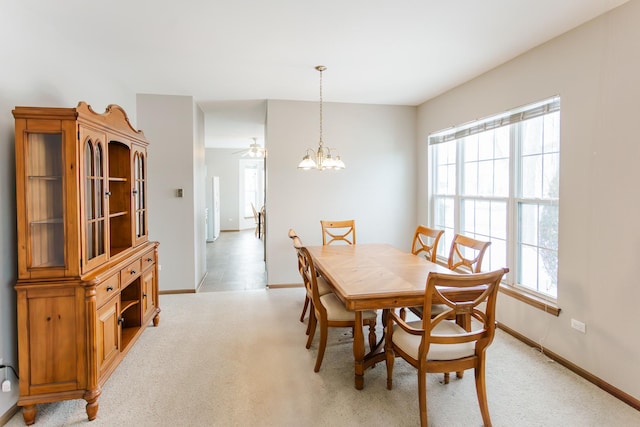 dining space featuring an inviting chandelier, baseboards, and light colored carpet