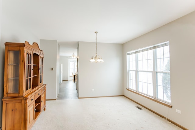 unfurnished dining area featuring carpet flooring and a notable chandelier