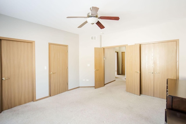 bedroom featuring light carpet, ceiling fan, visible vents, and two closets