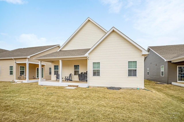 back of house featuring a shingled roof, a patio area, and a yard