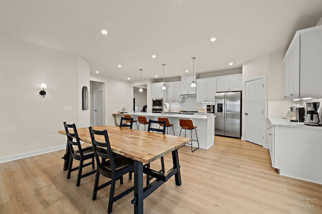 dining area with light wood-style floors, baseboards, arched walkways, and recessed lighting