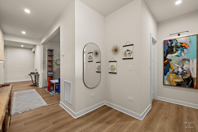 corridor with light wood-style floors, recessed lighting, visible vents, and baseboards