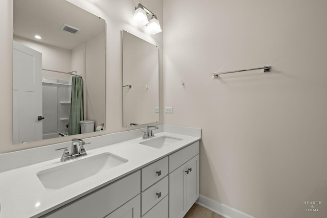 bathroom featuring visible vents, double vanity, a sink, and toilet