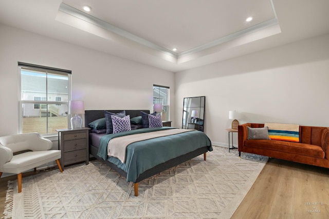 bedroom featuring baseboards, a tray ceiling, crown molding, light wood-style floors, and recessed lighting