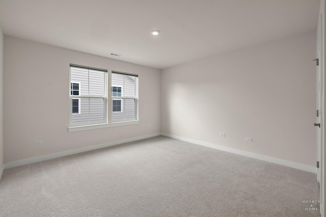 empty room with baseboards, visible vents, and light colored carpet