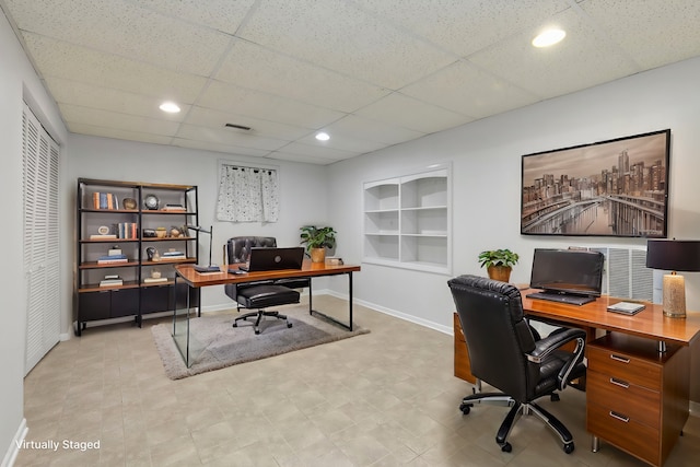 office with a paneled ceiling and built in features