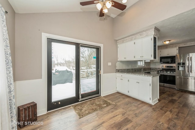 kitchen featuring stainless steel appliances, dark wood-style flooring, white cabinetry, and light stone countertops