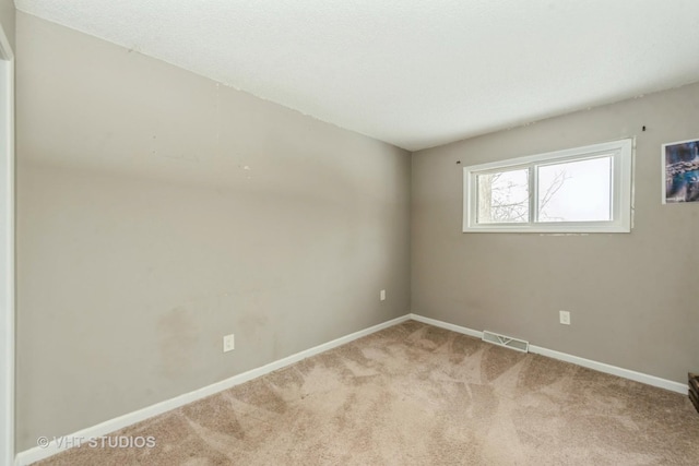 unfurnished room featuring carpet flooring, visible vents, and baseboards