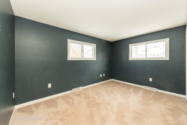 carpeted empty room with baseboards and visible vents