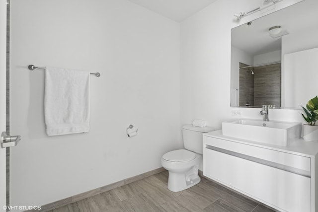 bathroom featuring vanity, wood-type flooring, a tile shower, and toilet