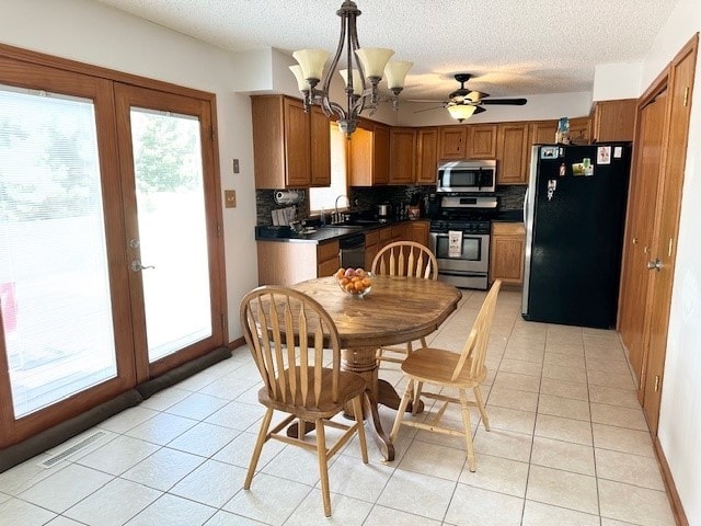 kitchen with a wealth of natural light, pendant lighting, light tile patterned floors, stainless steel appliances, and french doors