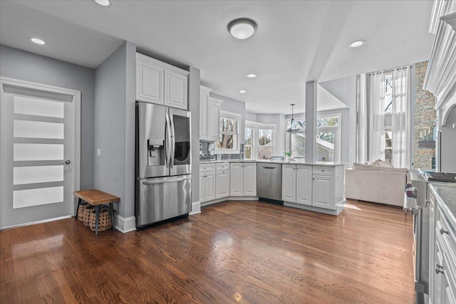 kitchen with dark wood-style floors, open floor plan, stainless steel appliances, white cabinetry, and pendant lighting