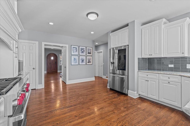 kitchen featuring light stone counters, white cabinetry, stainless steel appliances, and arched walkways