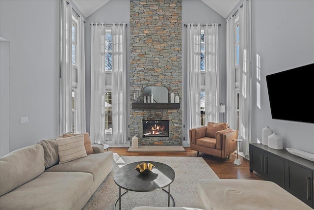 living area featuring a wealth of natural light, a fireplace, high vaulted ceiling, and dark wood-style flooring